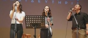 H κύριος ζερβουδάκης μαζί με δύο μαθήτριες των εκπαιδευτηρίων απαγγέλλουν στη σκηνή